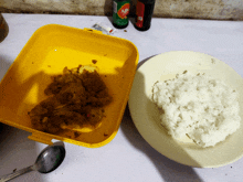 a plate of rice next to a yellow container of food