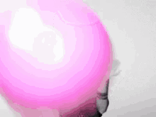 a woman is blowing up a pink balloon with bubble gum .