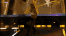 a blurry picture of a woman dancing on a stage with a wrestling logo in the background