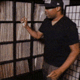 a man in a black shirt is standing in front of a shelf of records