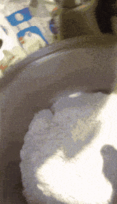 a close up of a bowl of flour with a bag of rice in the background