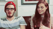a man and a woman are sitting on a couch and the woman is smiling at the man