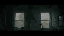 a man in a hooded sweatshirt is doing a handstand in a dark room .