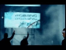 a blurry picture of people standing in front of a sign that says " bigbang "