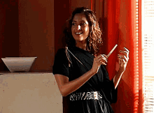 a woman in a black dress with a zebra print belt is holding a pair of scissors