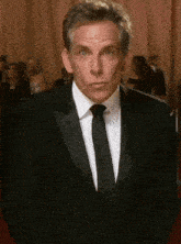 a man in a tuxedo and tie is making a funny face