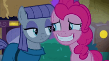 a couple of ponies are standing next to each other and one is smiling