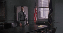a man in a police uniform stands in front of a table with an american flag in the background