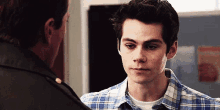 a young man in a plaid shirt is talking to another man