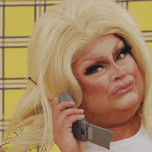 a drag queen talking on a cell phone while wearing a yellow plaid jacket
