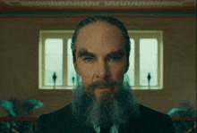 a man with a beard and moustache looks at the camera