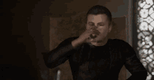 a man in a black shirt is holding a glass of wine