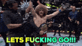 a man holding a ufc belt is being helped by a man with the words lets fucking go