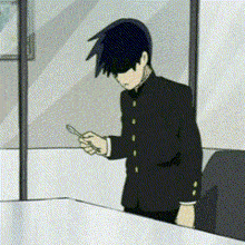 a man in a black suit is standing in front of a window looking at his cell phone .