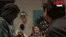 a man in a hooded jacket is talking to another man in a room with balloons and a sign that says lopez