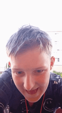 a young boy wearing a black shirt with a smiley face on it sticks out his tongue