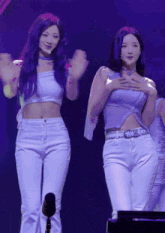 a woman with purple hair is standing next to another woman wearing white pants