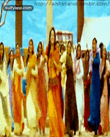 a group of women are dancing in front of a screen that says " kulfyapp.com "