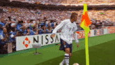 a soccer player is kicking a ball in front of a nissan banner