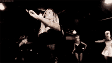 a group of women are dancing in a dark room in a video .