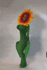 a woman in a green dress with a sunflower head and green leaves