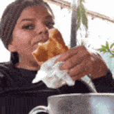 a woman is sitting at a table eating a piece of bread .