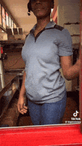 a woman in a blue shirt and blue jeans is standing in a kitchen