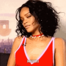 a woman with curly hair is wearing a red tank top and a necklace .