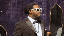 a man in a tuxedo and sunglasses stands in front of a sign that says adult swim.com