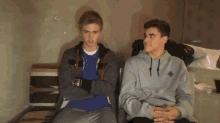 two young men are sitting next to each other smiling