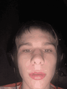 a young man wearing headphones looks at the camera with a red lip