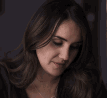 a woman wearing a black shirt and a silver necklace looks at the camera