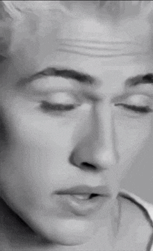 a black and white photo of a man 's face with a cigarette in his mouth
