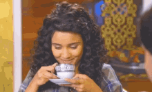 a woman with curly hair is drinking from a cup that says ' xoxo ' on it