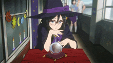 a girl in a witch hat is sitting at a table with a crystal ball