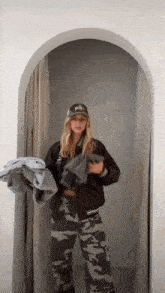 a woman is standing in a dressing room holding a jacket and pants .
