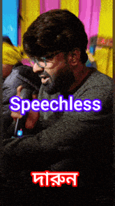 a man with glasses and a beard is holding a microphone and the word speechless is displayed above him
