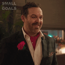 a man in a suit with a red flower in his pocket and the words small achievable goals on the bottom right