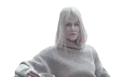 a woman in a sweater drinks from a glass