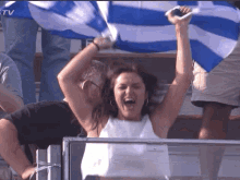 a woman holds a blue and white flag over her head in a crowd