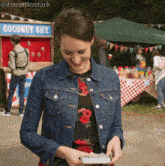 a woman is standing in front of a coconut shy booth