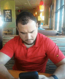 a man in a red shirt is looking at his phone