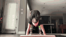 a woman is doing push ups on a yoga mat in front of a sign that says everton