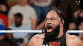 a wrestler with a beard is standing in a ring with his mouth open .