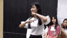 a girl in a white shirt is dancing in front of a group of girls .