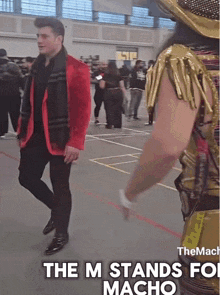 a man in a red jacket is standing next to a man in a gold outfit with the words the m stands for macho