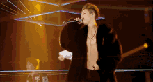 a man in a fur coat is singing into a microphone on stage .