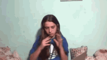 a girl with long hair is sitting on a bed with a laptop and eating a sandwich .