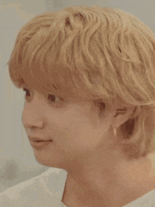a close up of a person 's face with blonde hair and earrings making a funny face .