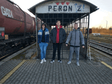 three young men standing in front of a sign that says peron